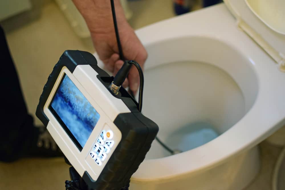 plumber using camera to inspect clog in toilet.